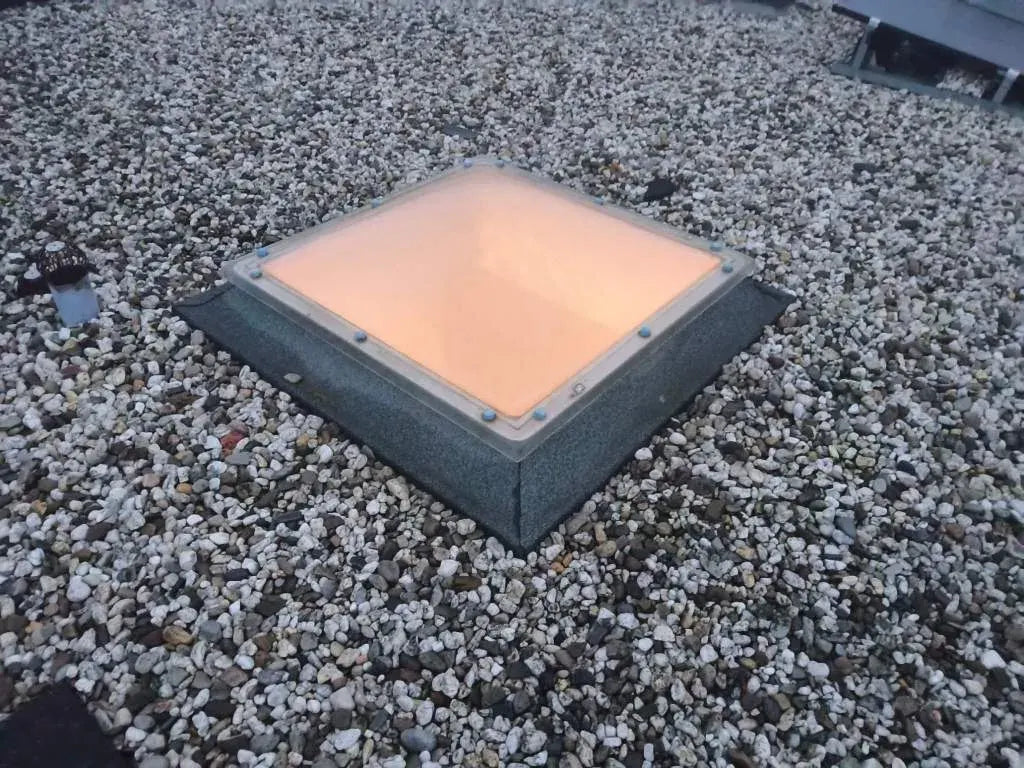 Lichtkoepel in een grinddak bij schemer