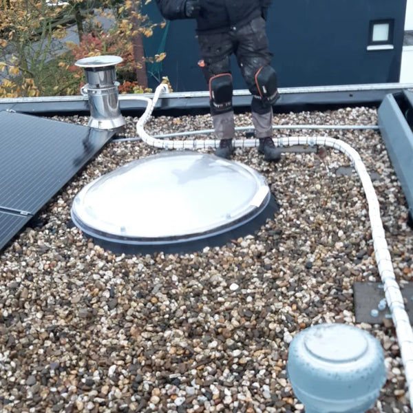 Ronde lichtkoepel op een grinddak, net geplaatst